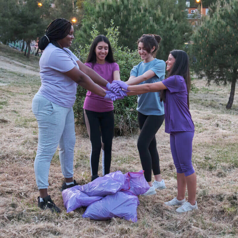 Group of multiracial active women putting their hands together after plogging.
